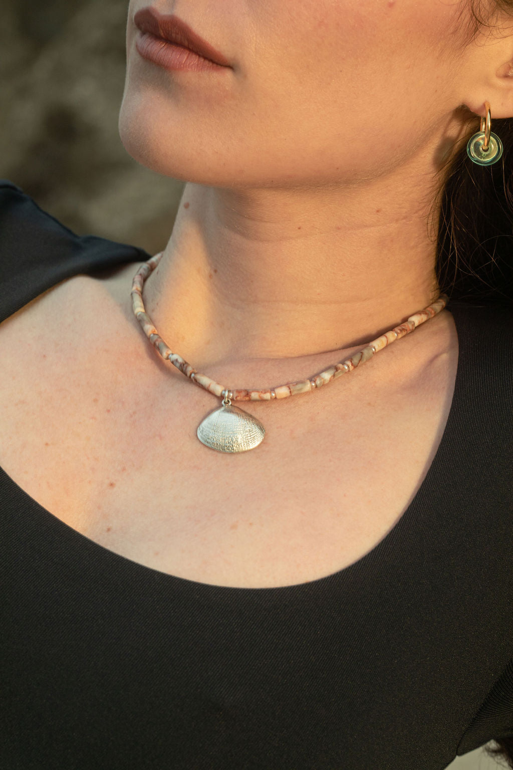 Close-up of the Caroline Necklace, featuring jasper and freshwater pearls with a sterling silver-plated clam shell pendant, paired with Keeley I Earrings in Turquoise, gold-plated hoops with handblown turquoise glass beads.