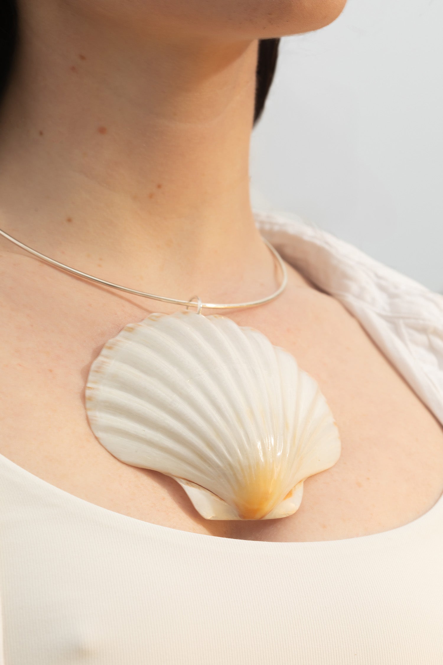 Close-up of the Marina Necklace featuring a sterling silver neck wire and an Irish scallop shell pendant. The shot highlights the pendant’s natural texture and sculptural form, reflecting the ocean’s influence on minimal, modern jewelry design.
