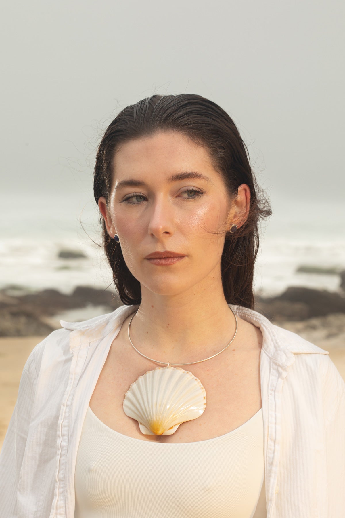Close-up of the Marina Necklace, featuring a textured Irish scallop shell pendant on a silver wire choker, styled with the Mabel Earrings—elegant lapis lazuli gemstone studs in sterling silver.