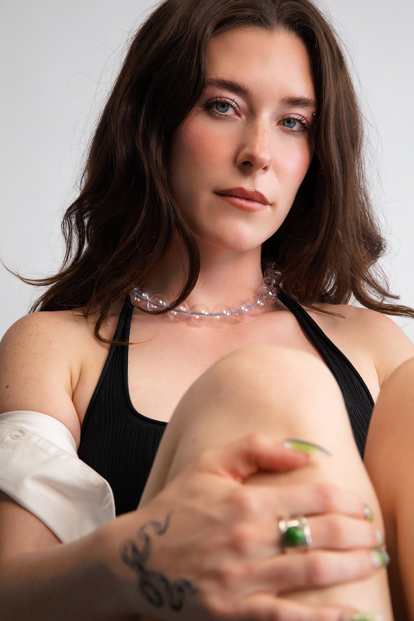 Model wearing a clear pink beaded necklace. Each bead is hand blown glass and strung on a grey leather cord.