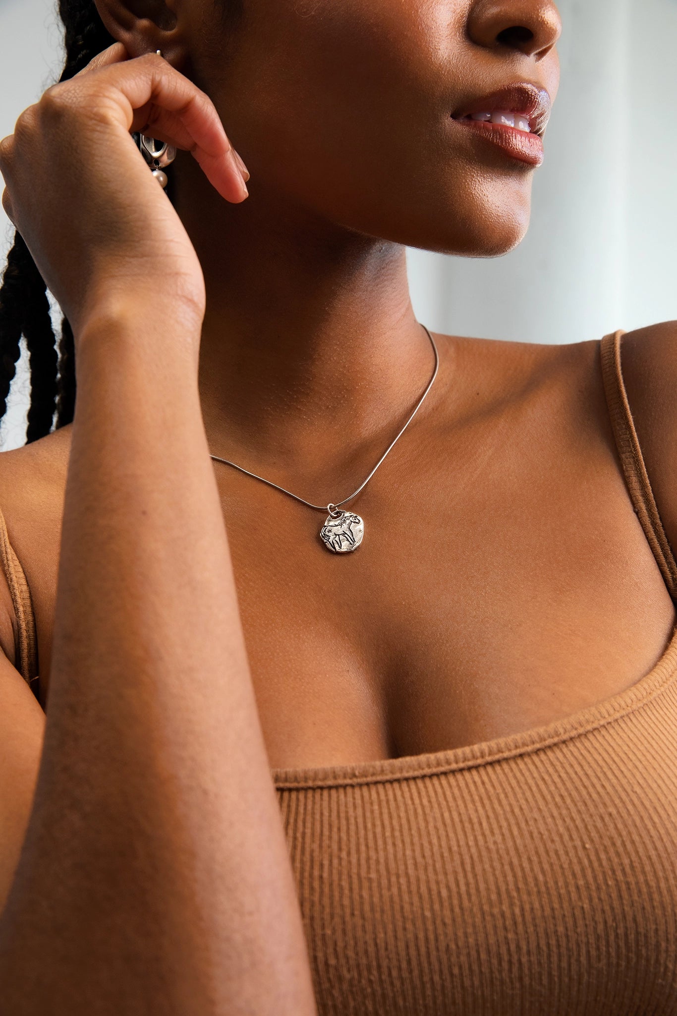 A model wearing a Sterling Silver necklace with a hand cast horse pendant.