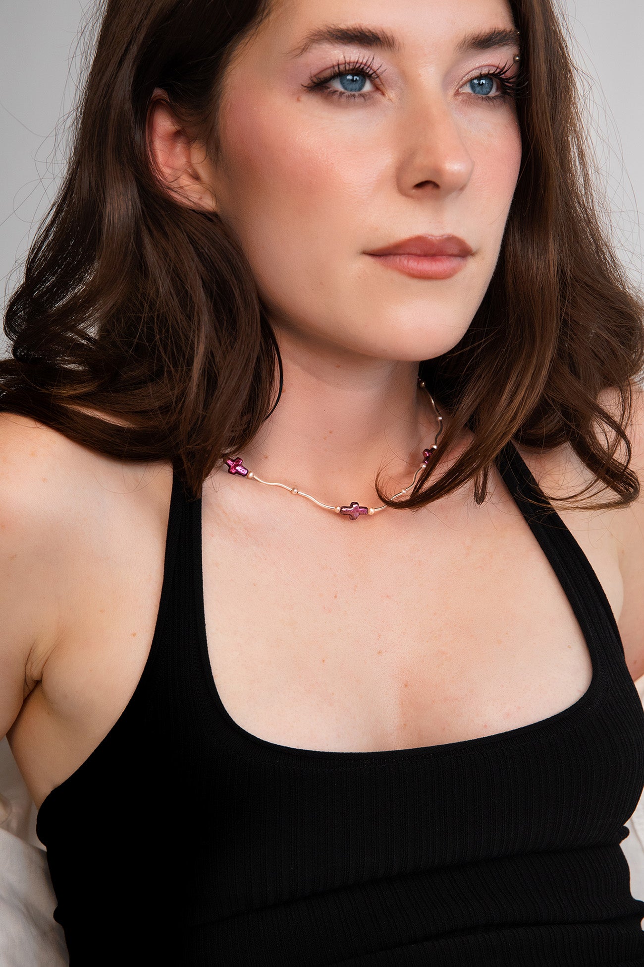 Model wearing a dainty necklace featuring solid .925 Sterling Silver curved tubes, cherry red freshwater pearl crosses, and AAA-quality freshwater pearls.