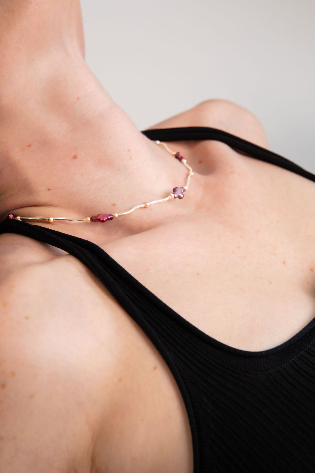 Model wearing a dainty necklace featuring solid .925 Sterling Silver curved tubes, cherry red freshwater pearl crosses, and AAA-quality freshwater pearls.