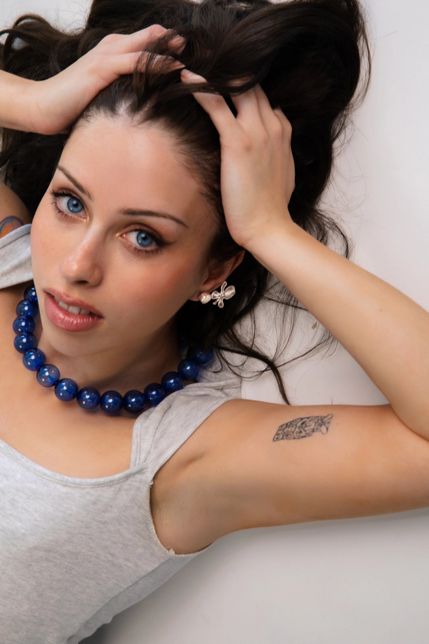 A model wearing a clear cobalt blue beaded necklace. Each bead is hand blown glass and strung on a blue leather cord.