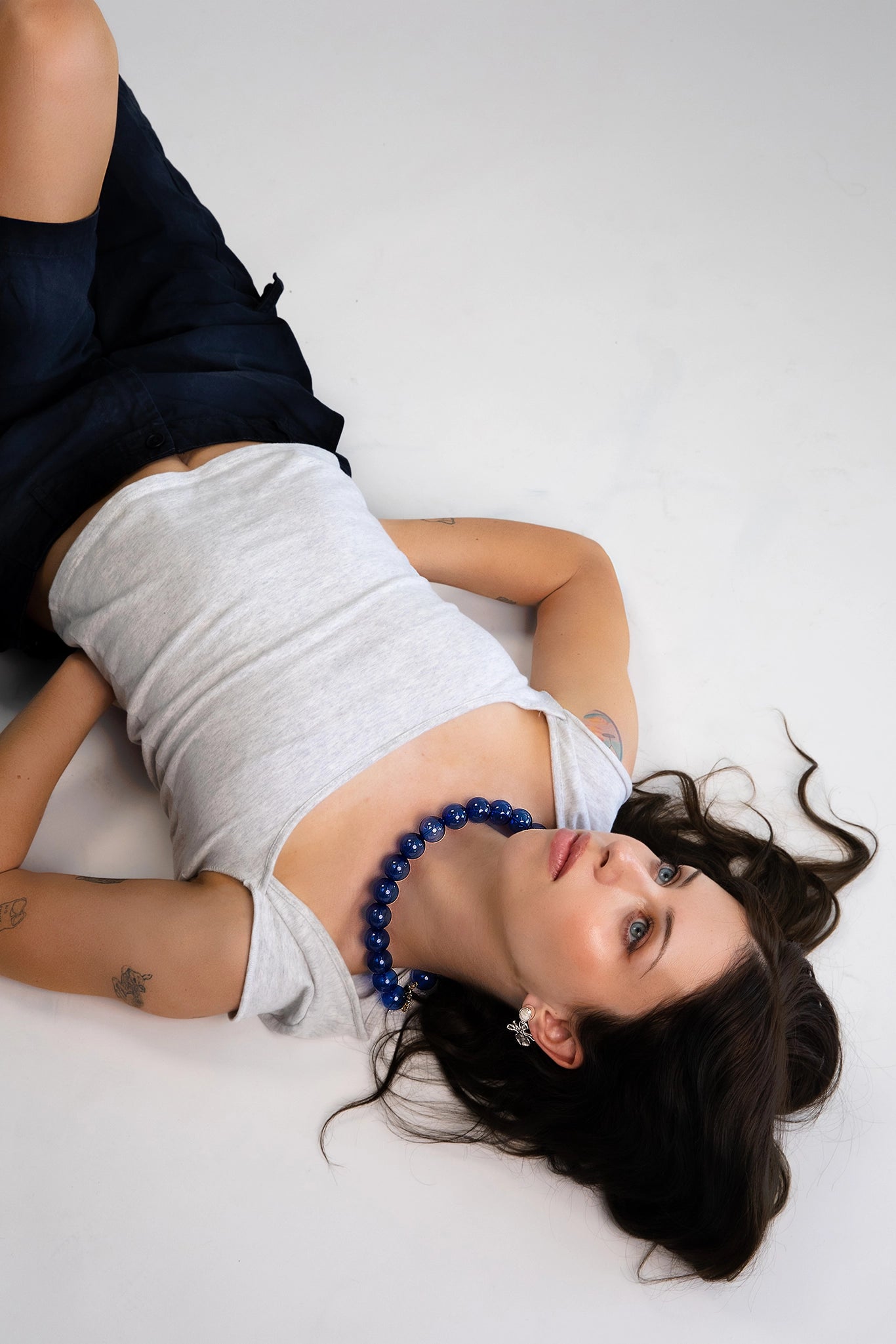 A model wearing a clear cobalt blue beaded necklace. Each bead is hand blown glass and strung on a blue leather cord.