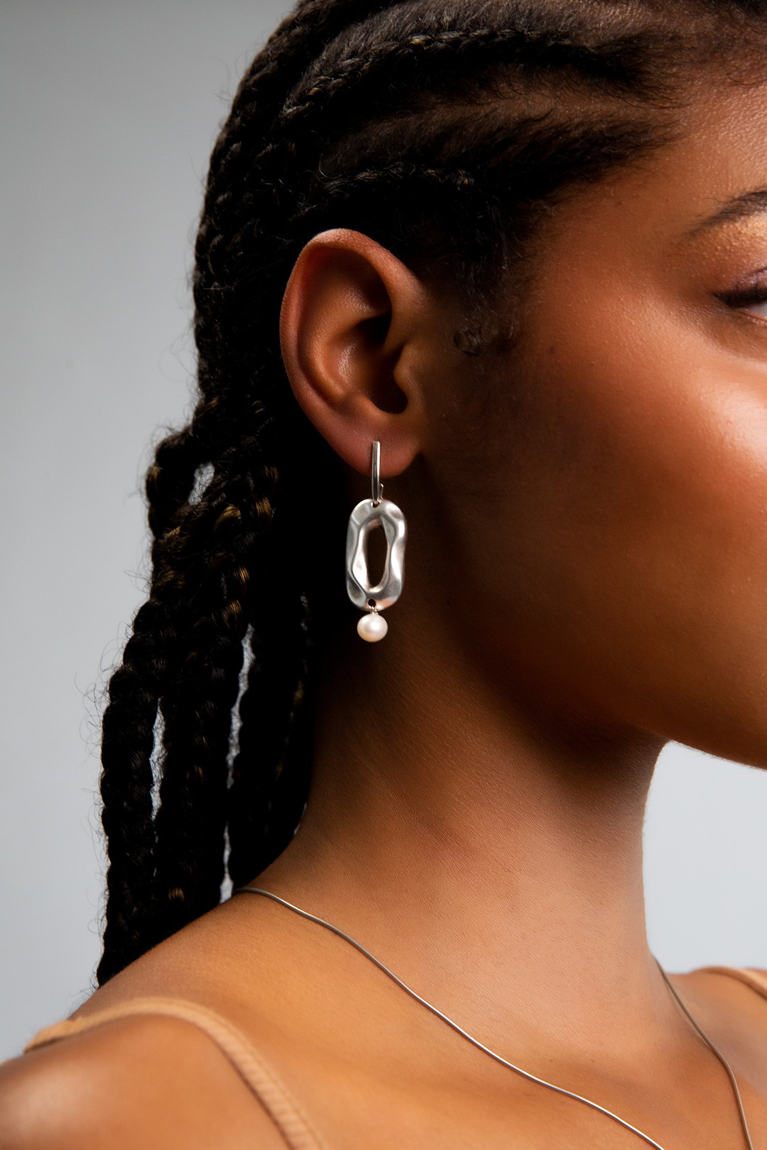 Model wearing solid .925 Sterling Silver earrings that feature geometric shapes hand cast in Sterling Silver plating, adorned with AAA-quality freshwater pearls for a touch of sophistication.