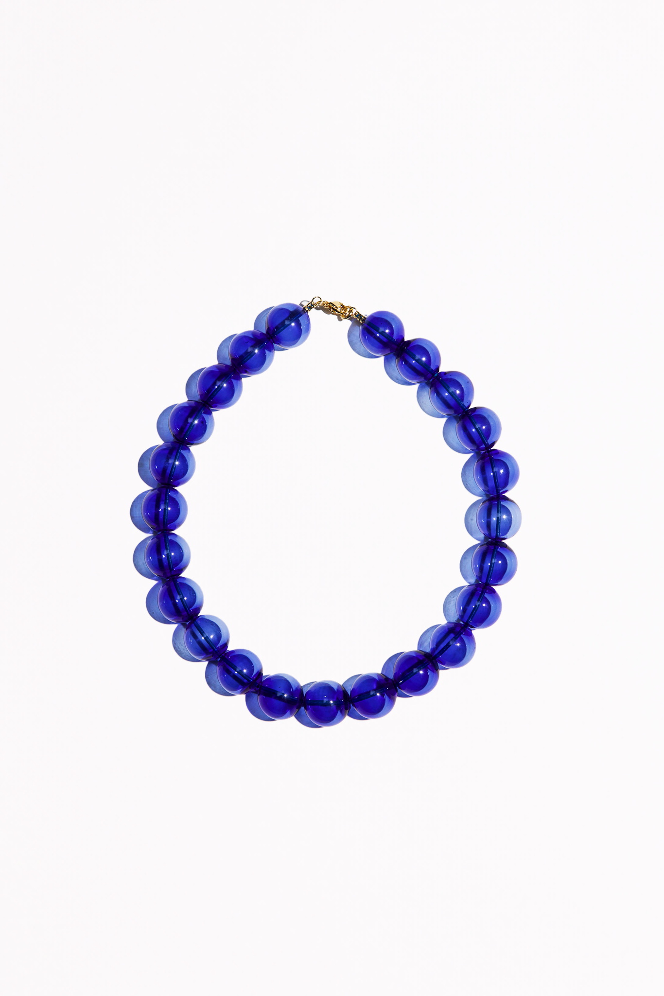 Clear cobalt blue beaded necklace. Each bead is hand blown glass and strung on a blue leather cord.