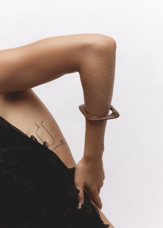 Arch Bangle in natural wood worn on wrist, sculptural square shape visible against skin.