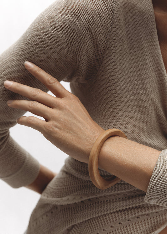 The Dunes Bangle — hand-carved wooden bangle with a matte finish worn on wrist.