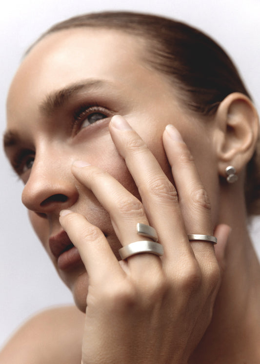 Model wearing the Eros Ring, a delicate silver stackable ring, styled with other sterling silver rings.