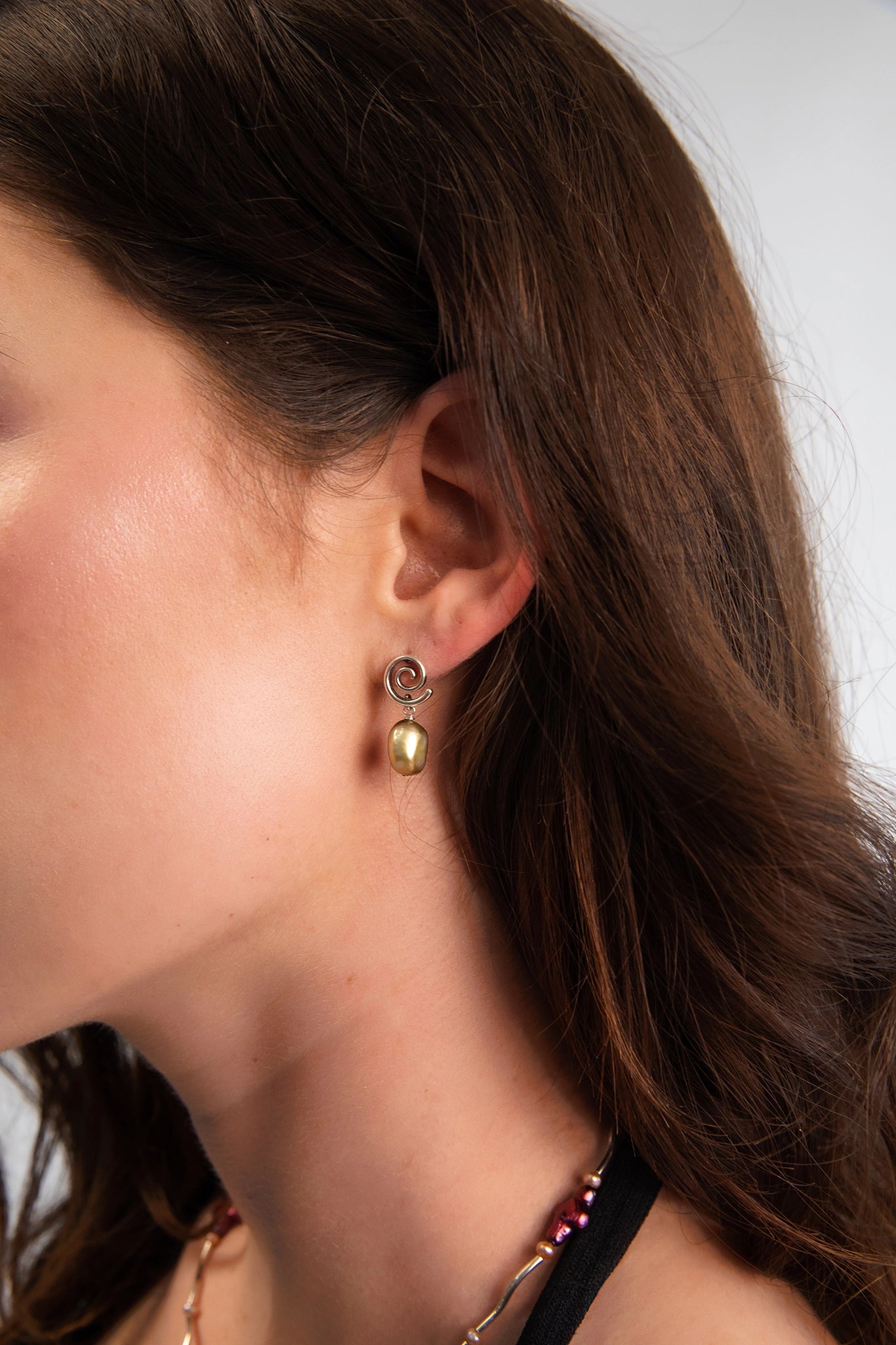 Model wearing solid .925 Sterling Silver spiral earrings with freshwater baroque pearl drops. 