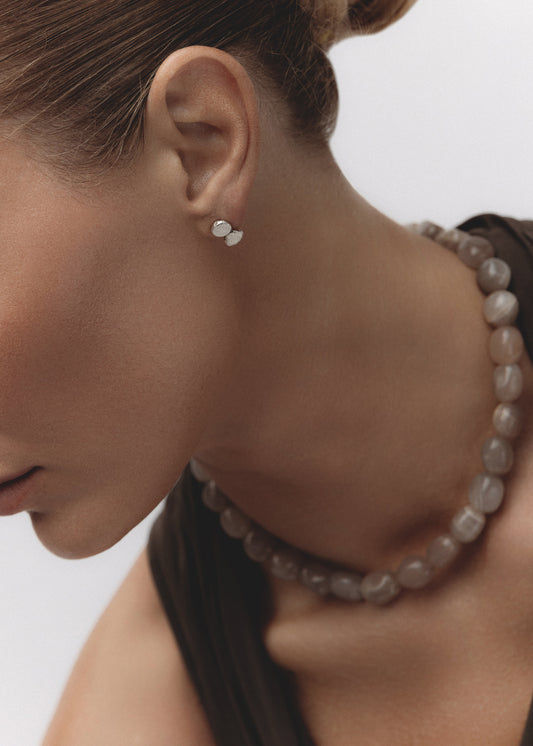 Model wearing the Mirage Earrings — organic sterling silver pebble studs, paired with a chunky grey moonstone necklace.