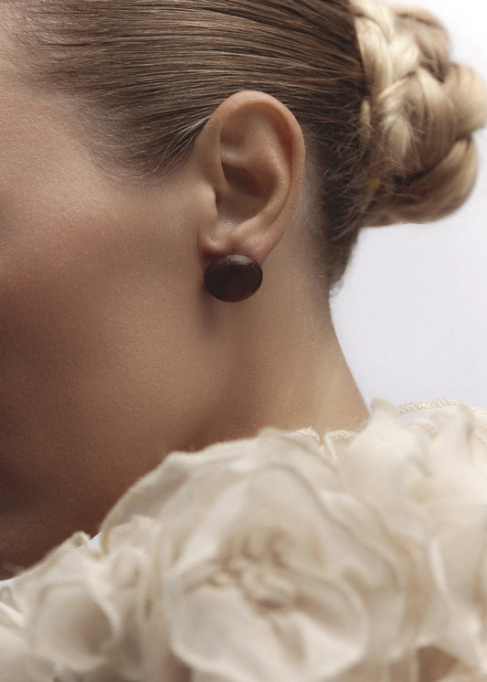 Model wearing the Mound Earrings — natural wood dome studs with 14k gold-filled posts, styled as statement stud earrings.