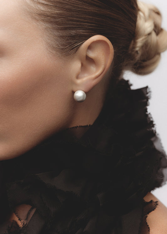 Model wearing the Orb Earrings — oversized statement ball studs in sterling silver, styled with a minimal look.