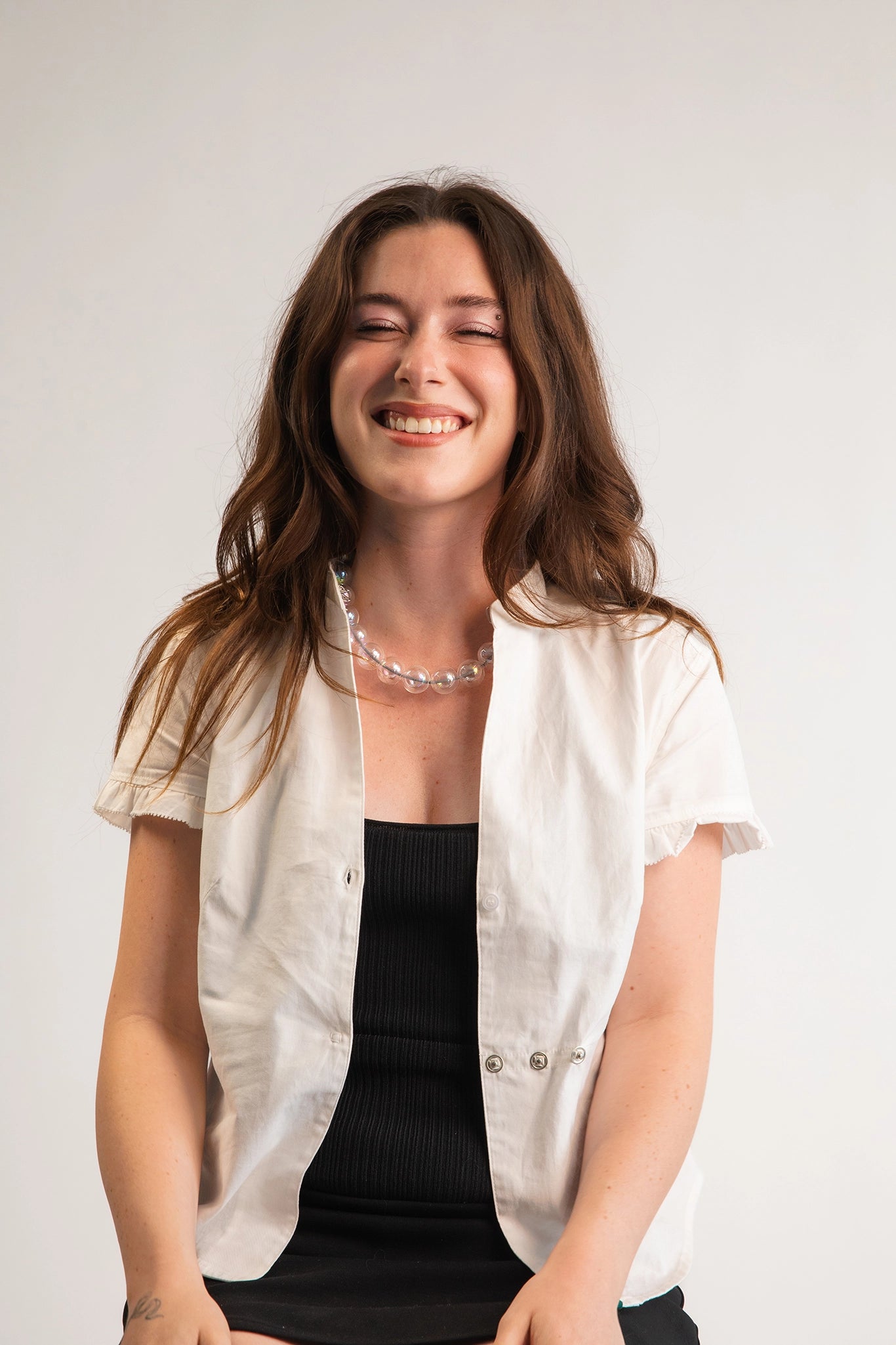 A model wearing a clear beaded necklace. Each bead is hand blown glass and strung on a gray leather cord.